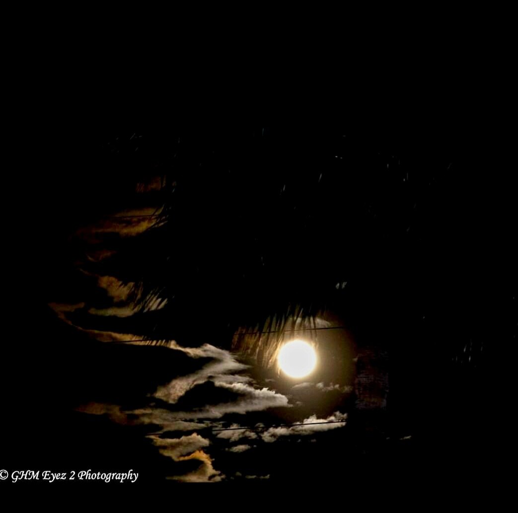 The moon breaking through sculpted clouds in a dark sky