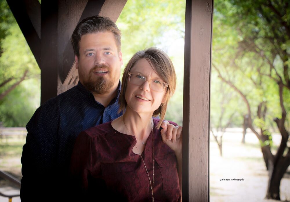 A couple framed together beside a window