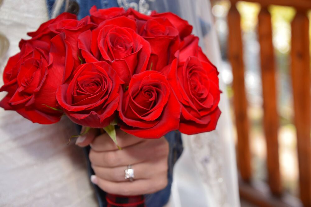 A vivid bouquet of red roses held by a bride