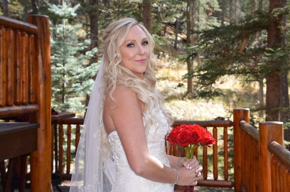 A bride holding a bouquet of red roses at an outdoor wedding