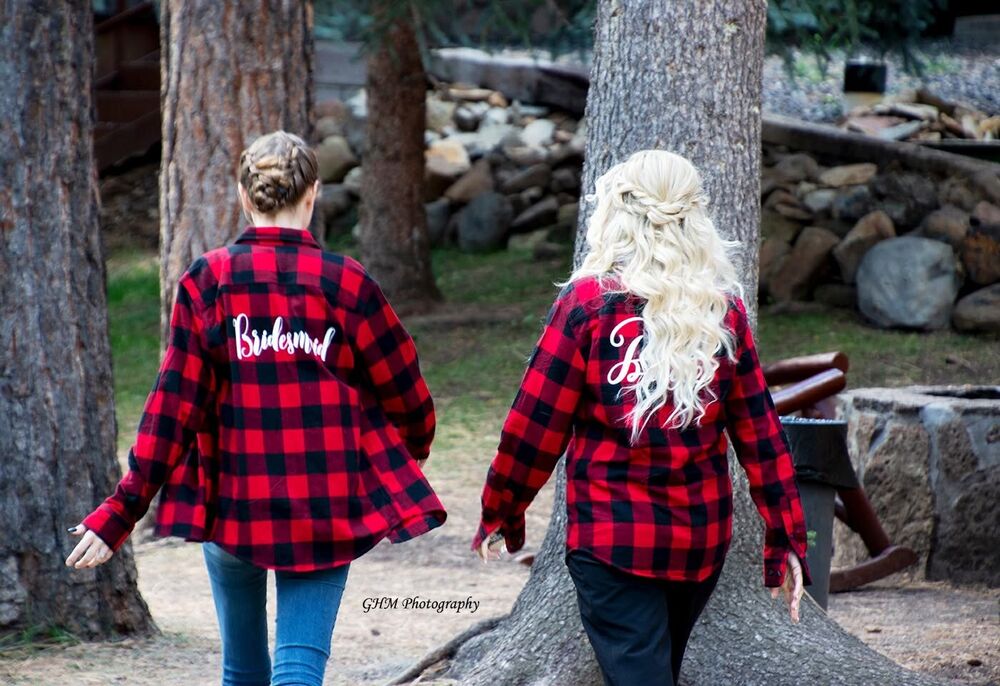 Two women in matching plaid shirts walking together through the trees