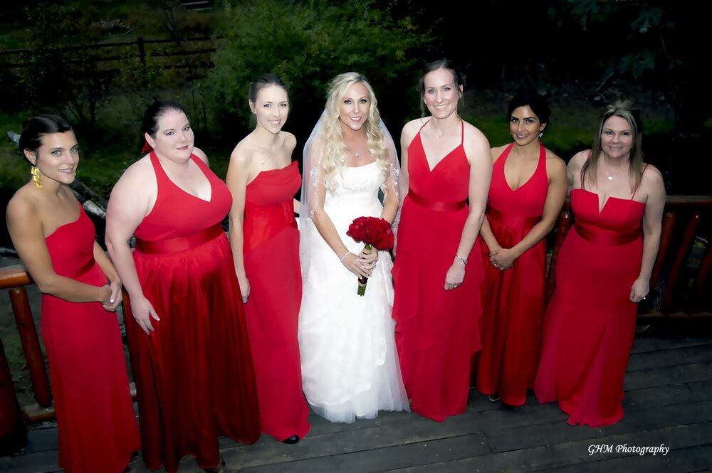 A bride with her attendants dressed in red at an outdoor wedding