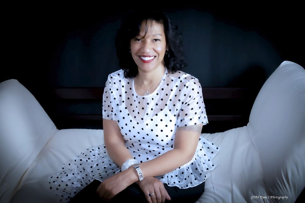 Professional portrait of a smiling woman seated against a dark backdrop