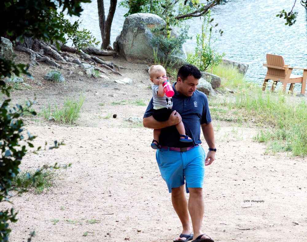 A father carrying his young child along a wooded path