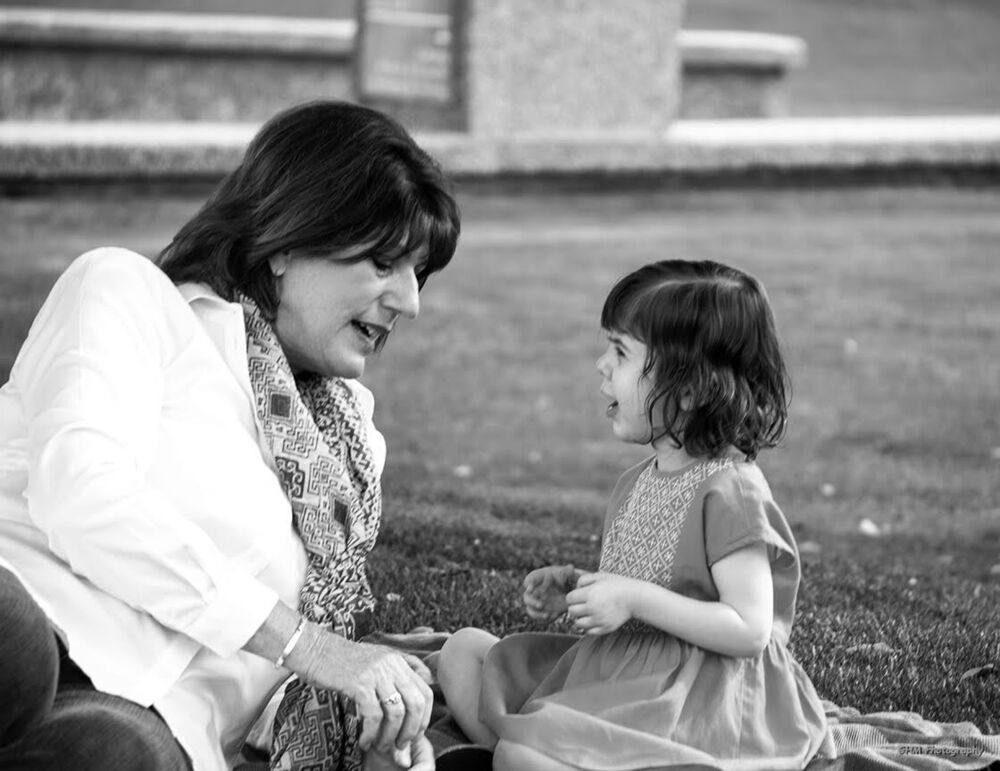 A woman and young girl sharing a conversation outdoors in black and white