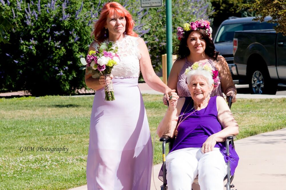 A bride arriving at an outdoor wedding ceremony with loved ones