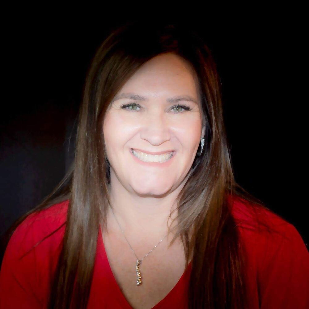 Professional portrait of a smiling woman in red against a dark backdrop