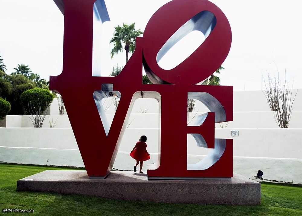 A child framed beneath a monumental LOVE sculpture