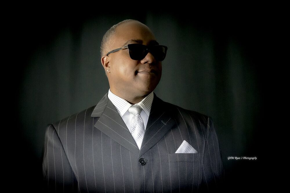 Formal portrait of a man in a striped suit and sunglasses