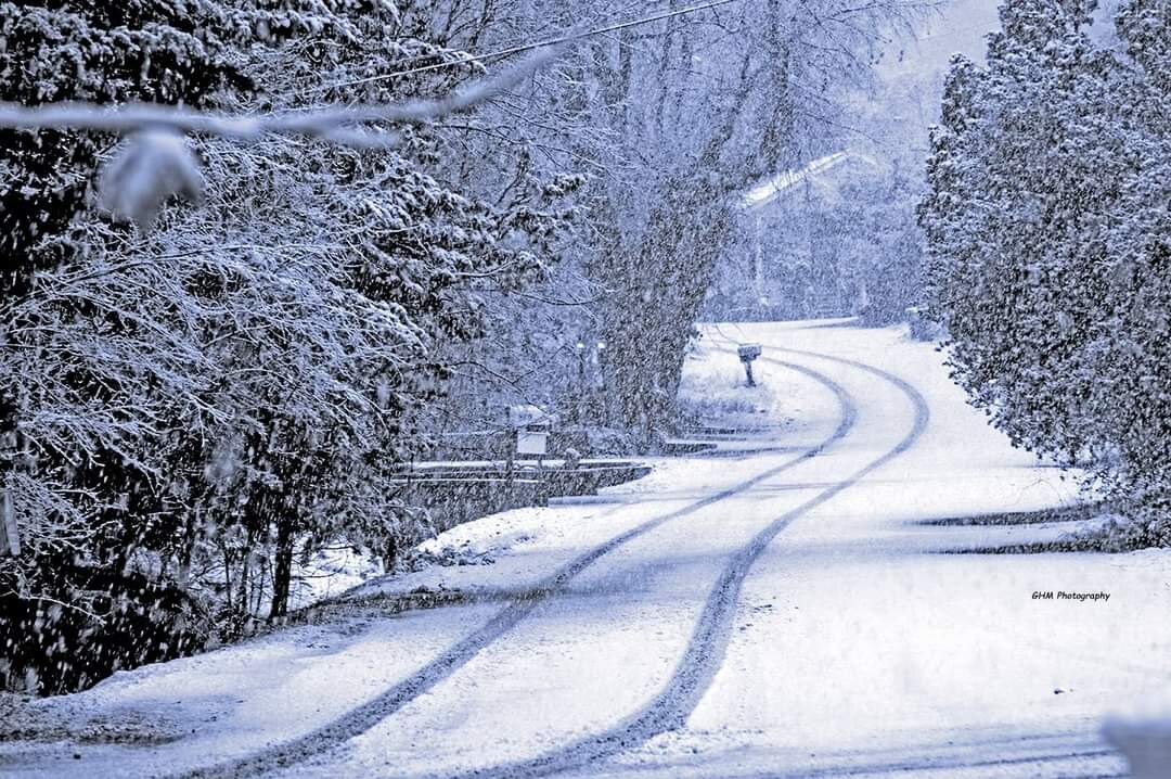 A snow-covered road winding through a quiet winter landscape